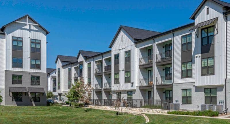 Four-story townhouse-style multifamily buildings under a blue sky